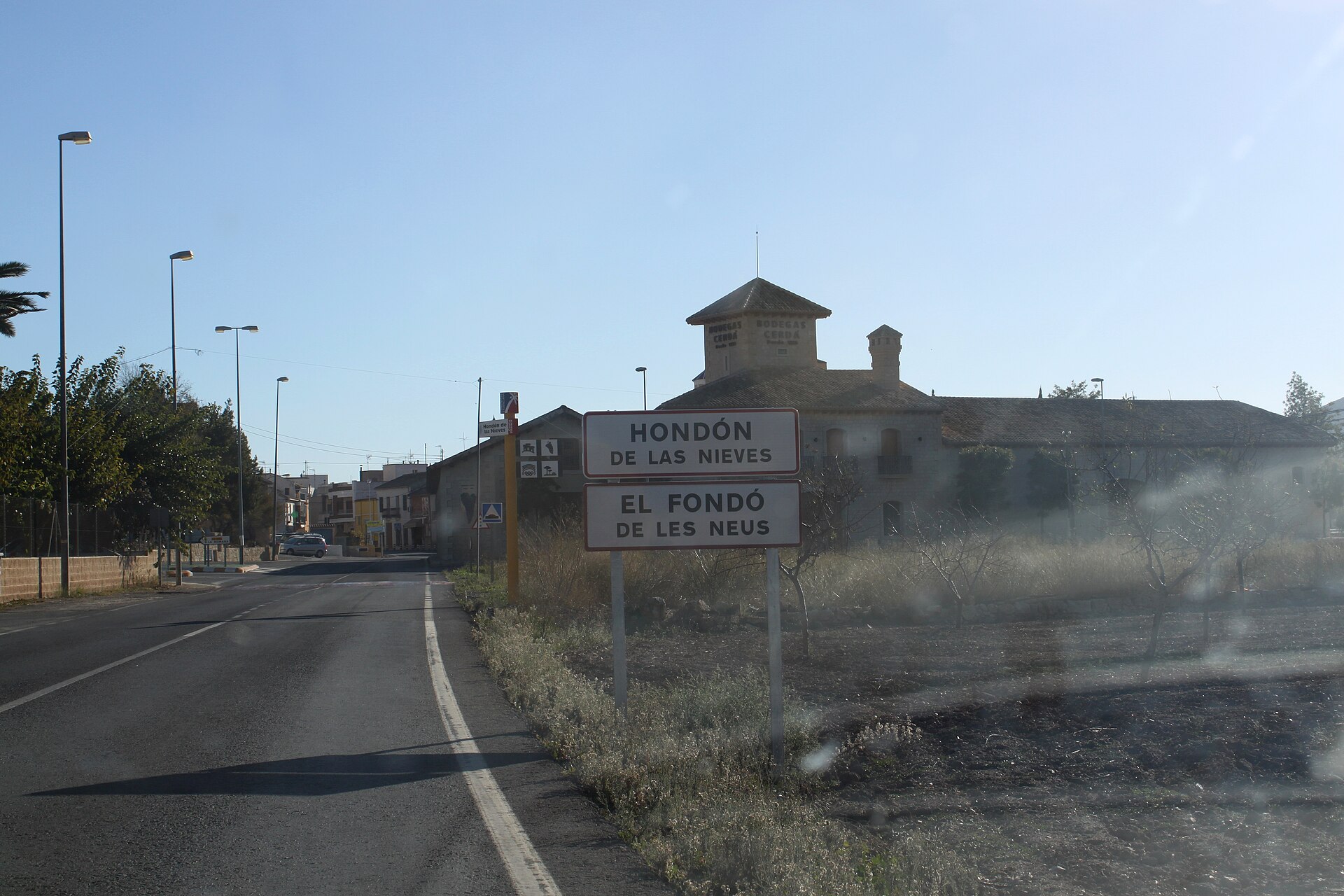 Cartel de entrada a Hondón de las Nieves junto a la carretera y edificio tradicional