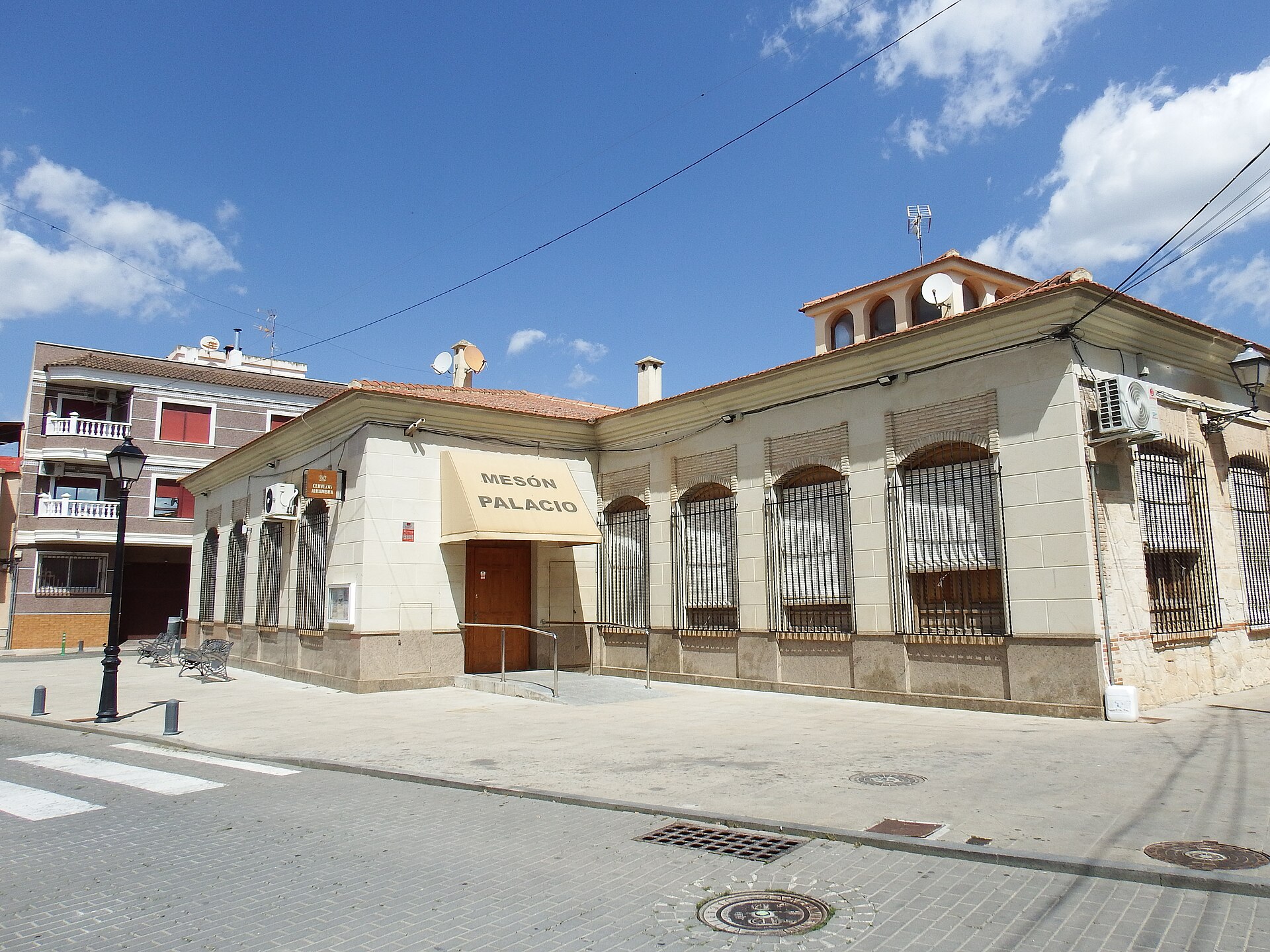 Jacarilla, fachadas con rótulo 'Mesón Palacio' y torre de iglesia al fondo