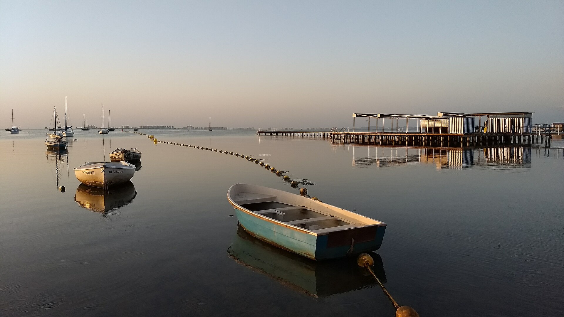 Embarcaciones y pontón en la calma del Mar Menor desde el Paseo del Atalayón en Santiago de la Ribera